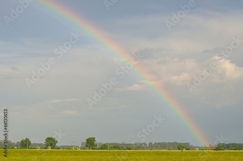Rainbow with cloudy sky after rain over field