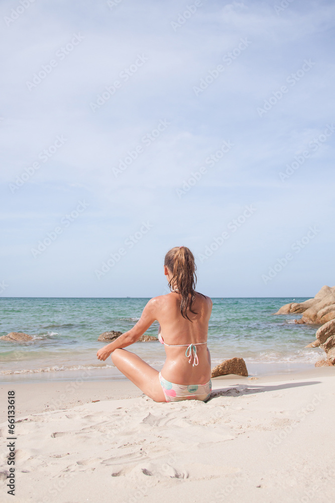 young woman meditating on the beach