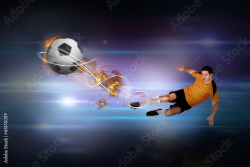 Composite image of football player in orange kicking © WavebreakMediaMicro