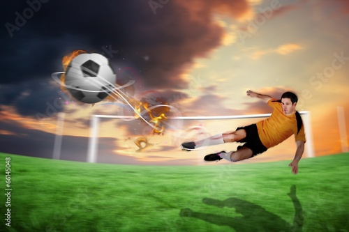 Composite image of football player in orange kicking © WavebreakMediaMicro