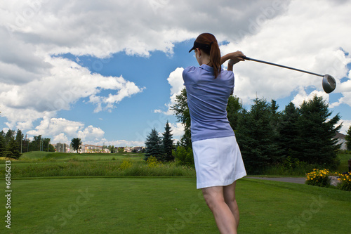 Female golfer swinging her golf club