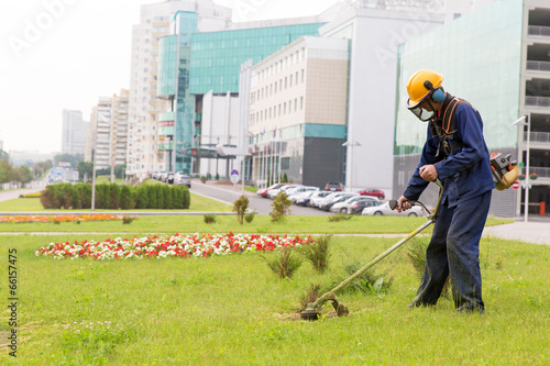 City landscaper mowing lawn wih gas trimmer photo