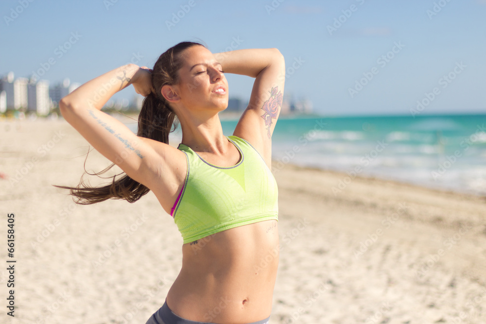 Fit hispanic woman stretches on the beach after a run Fit hispanic woman stretches on the beach after a run