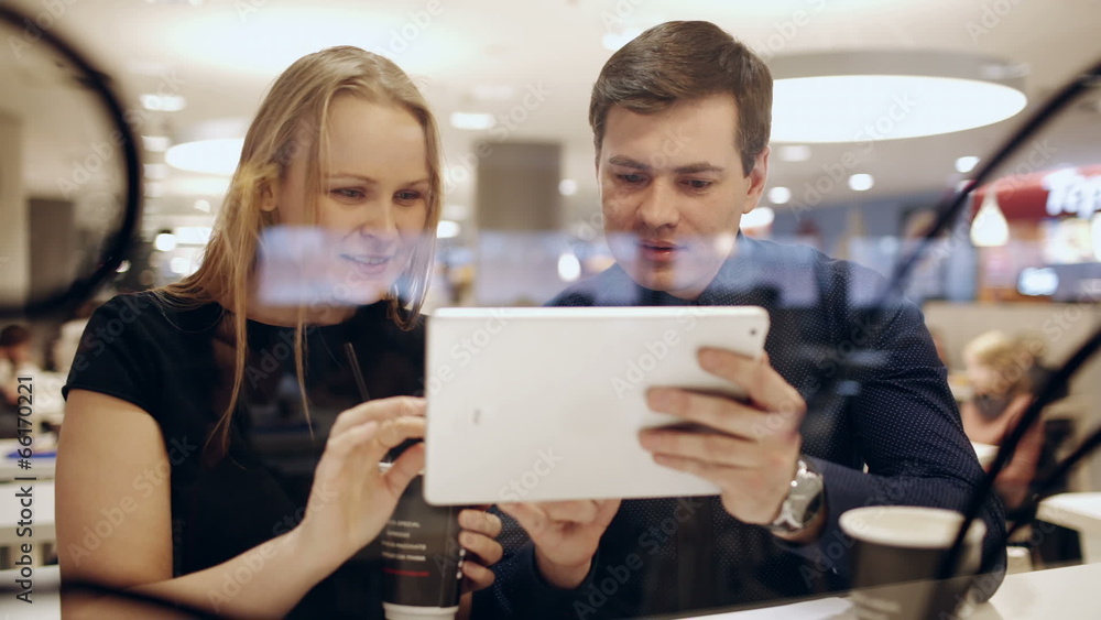 Man and woman in cafe talking vividly about something shown on Man and woman in cafe talking vividly about something shown on