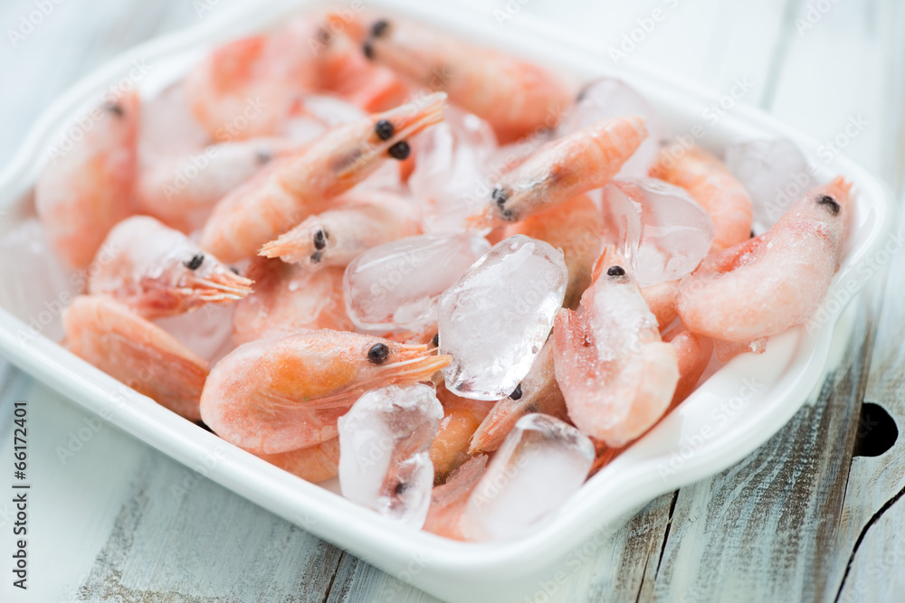 Raw shrimps on ice in a glass bowl, horizontal shot Raw shrimps on ice in a glass bowl, horizontal shot