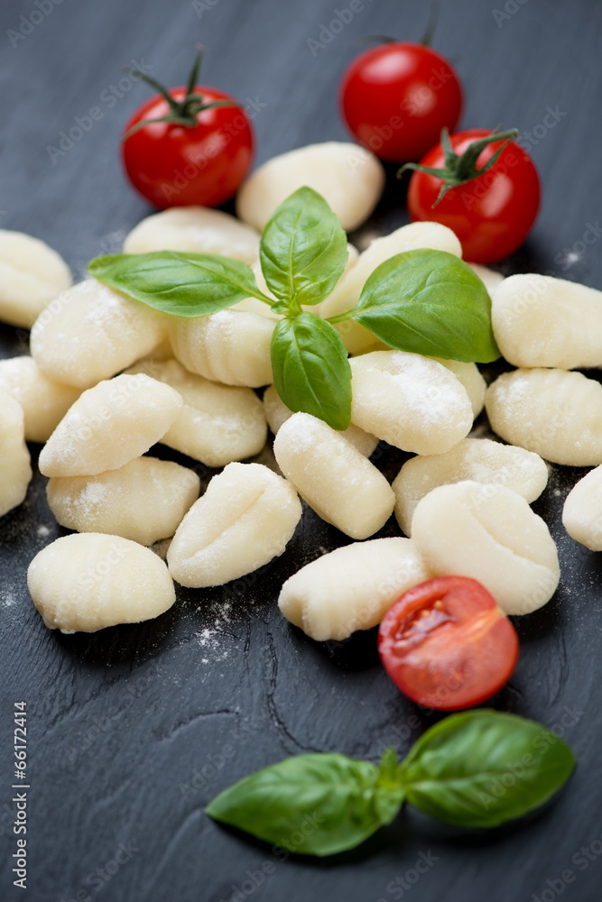 Raw gnocchi with red cherry tomatoes and green basil, close-up Raw gnocchi with red cherry tomatoes and green basil, close-up