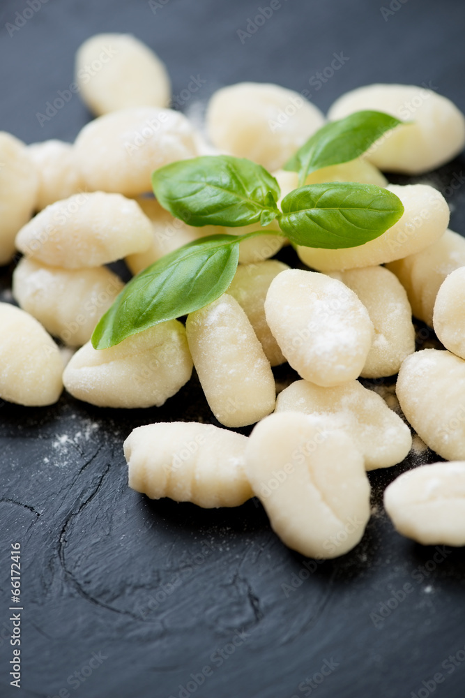Vertical shot of raw gnocchi with green basil leaves, close-up