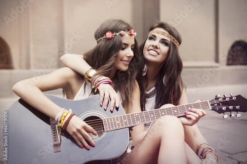 Beautiful stylish friends playing guitar