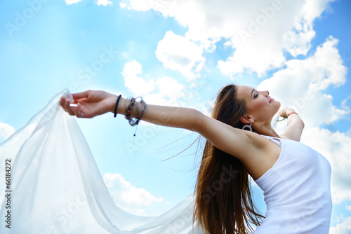 Happy young woman holding white scarf with opened arms expressin photo