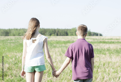 Boy holding girl's hand on green field