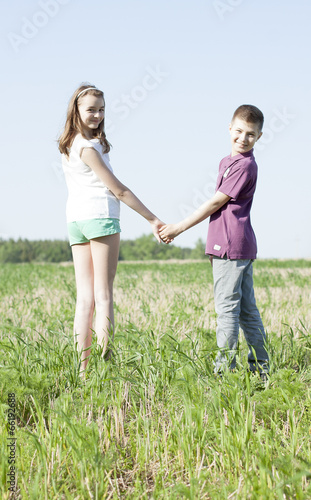 Boy holding girl's hand on green field