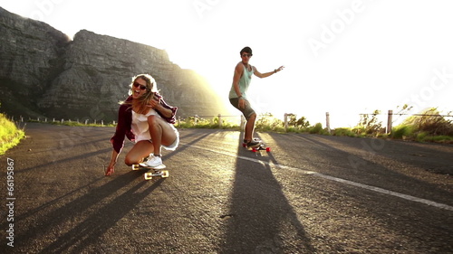 Friends longboard skating on road sunset photo