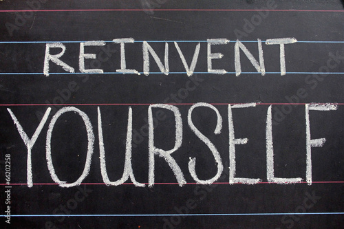 reinvent yourself phrase handwritten on black chalkboard