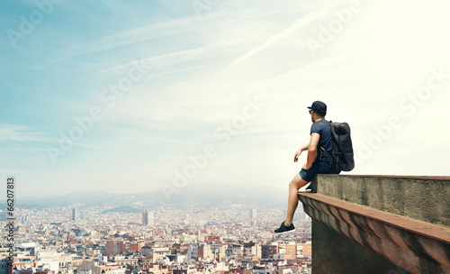young man sitting on a roof and looking city