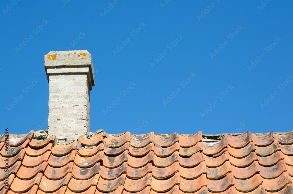 Chimney at an old broken tiled roof