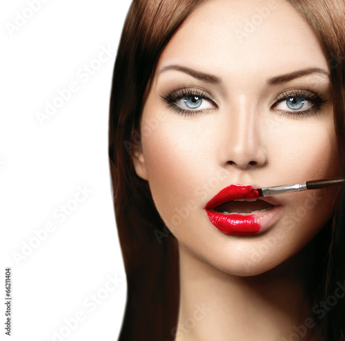 Beauty fashion model girl applying red lipgloss