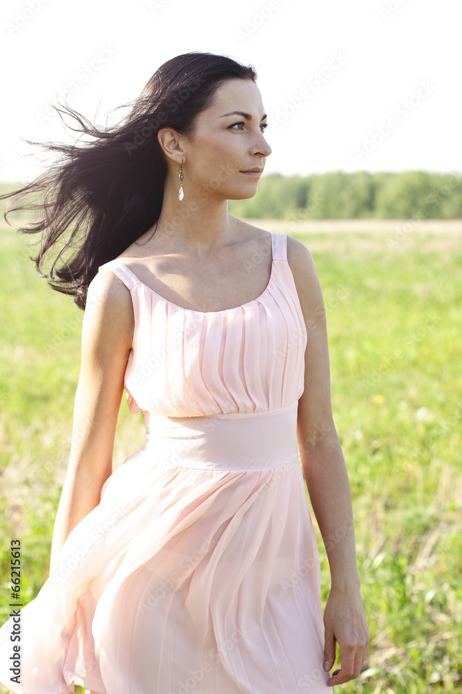 Beautiful woman in pink dress standing in a field Beautiful woman in pink dress standing in a field