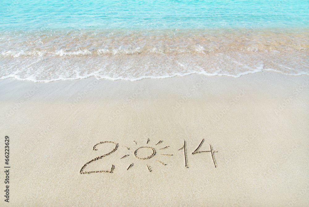Fototapeta premium inscription 2014 on sea sand beach with the sun rays