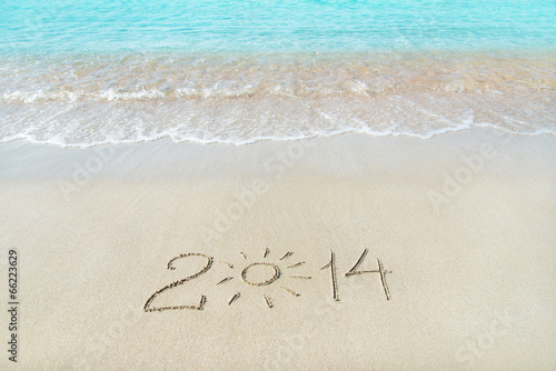 inscription 2014 on sea sand beach with the sun rays