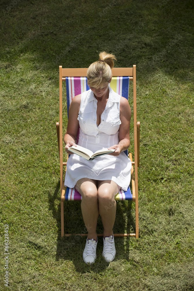 Woman sitting on a deck chair reading a book Woman sitting on a deck chair reading a book
