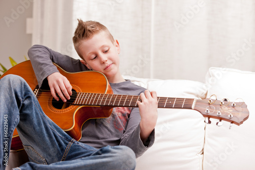 little boy playing guitar at home