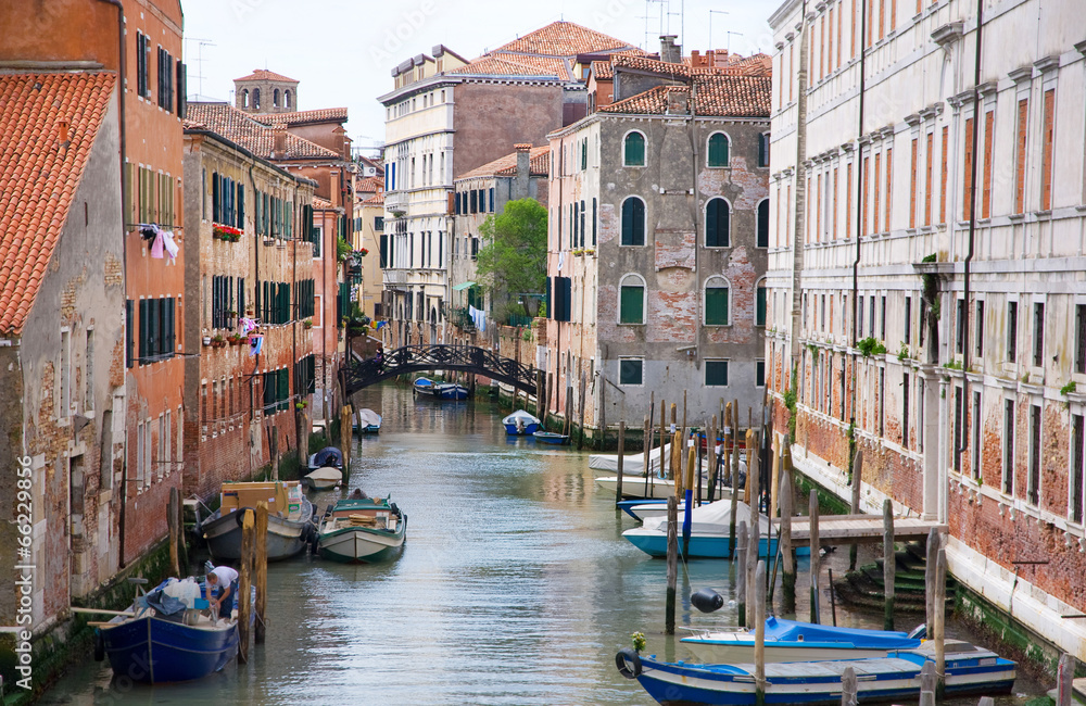 Venice canal with gondolas, boats and small bridge. Italy