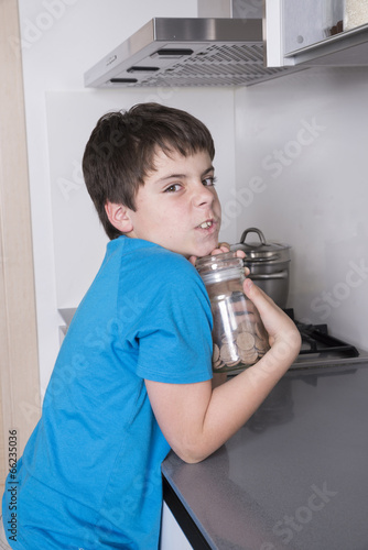 young boy taking candy from a high kitchen cabinet