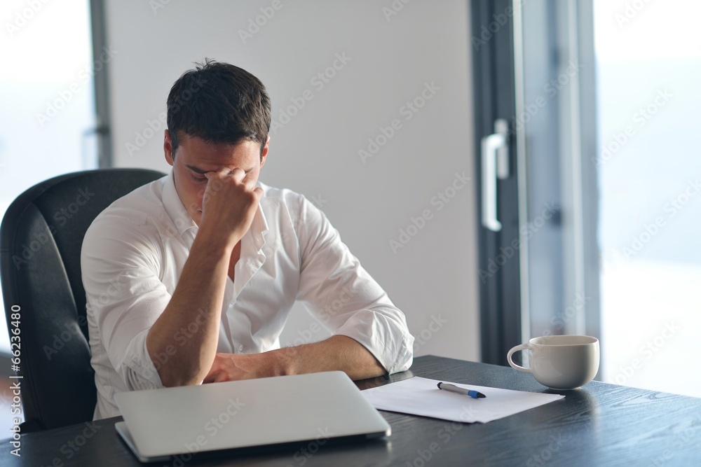 Naklejka premium frustrated young business man working on laptop computer at home