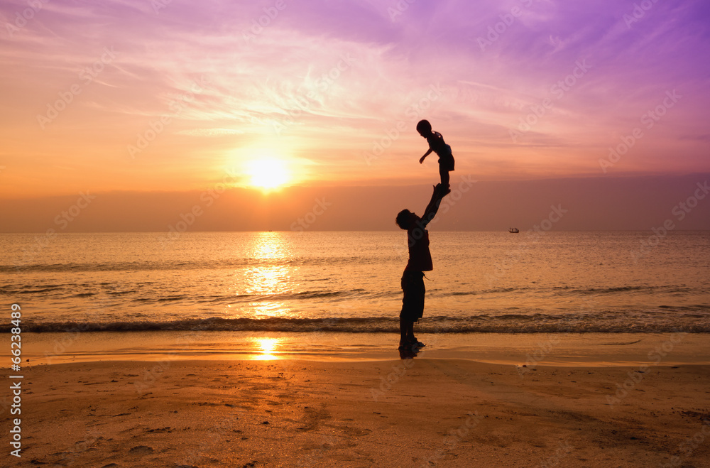 father and son on sunset beach,silhouette