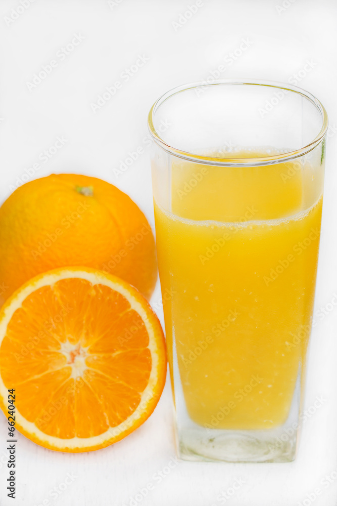 Glass of freshly pressed orange juice with sliced orange on woo Glass of freshly pressed orange juice with sliced orange on woo