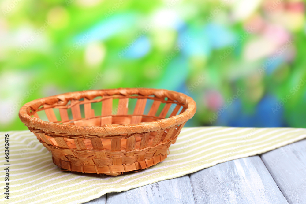 Fototapeta premium Empty wicker basket on wooden table, on bright background