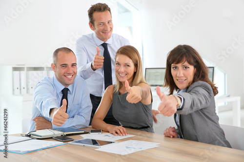 Cheerful business team showing thumbs up