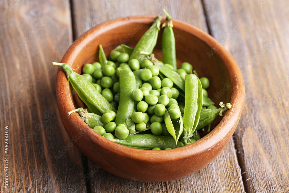 Green peas in wooden bowl on wooden background Green peas in wooden bowl on wooden background