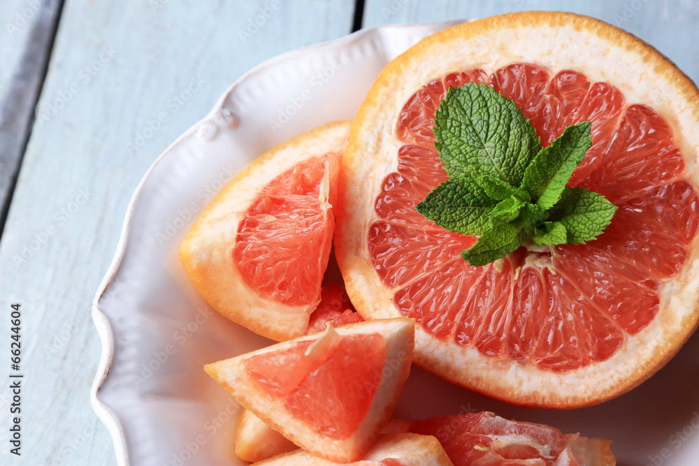 Ripe grapefruits on plate on color wooden background Ripe grapefruits on plate on color wooden background