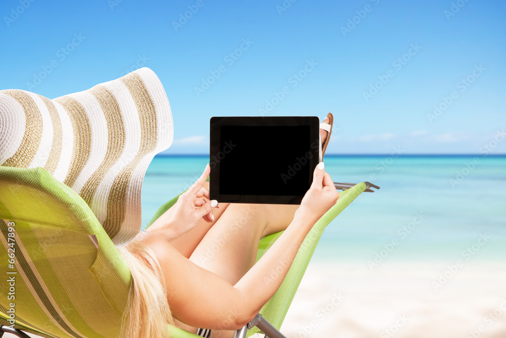 Blond girl with tablet on tropical beach