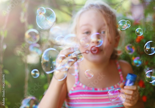 Little girl blows soap bubbles outdoor
