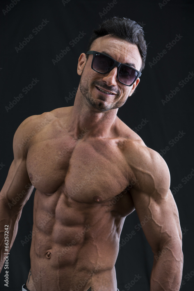 Shirtless muscular young man with sunglasses, smiling