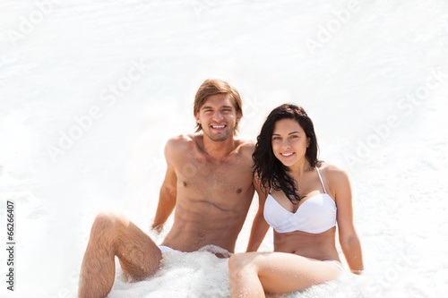 Couple on beach  sitting in water wave foam sea