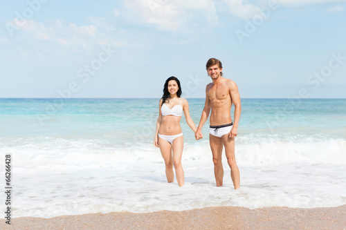 Couple on beach standing in water wave foam