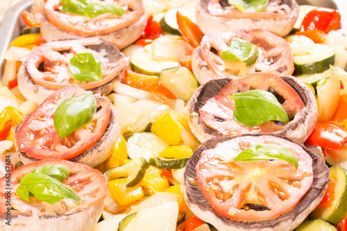 Raw mushrooms with cooked vegetables and leafs of basil photo