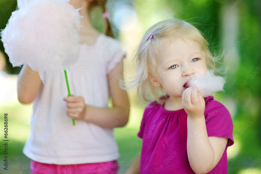 Adorable little sisters eating candy-floss Adorable little sisters eating candy-floss