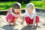 Two little sisters playing in a sandbox