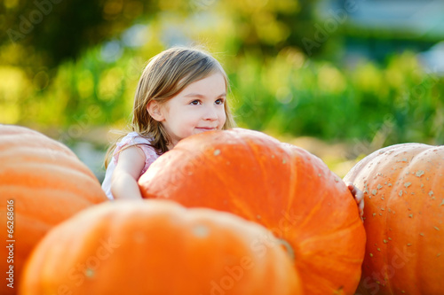 Adorable little girl embracing big pumpkin
