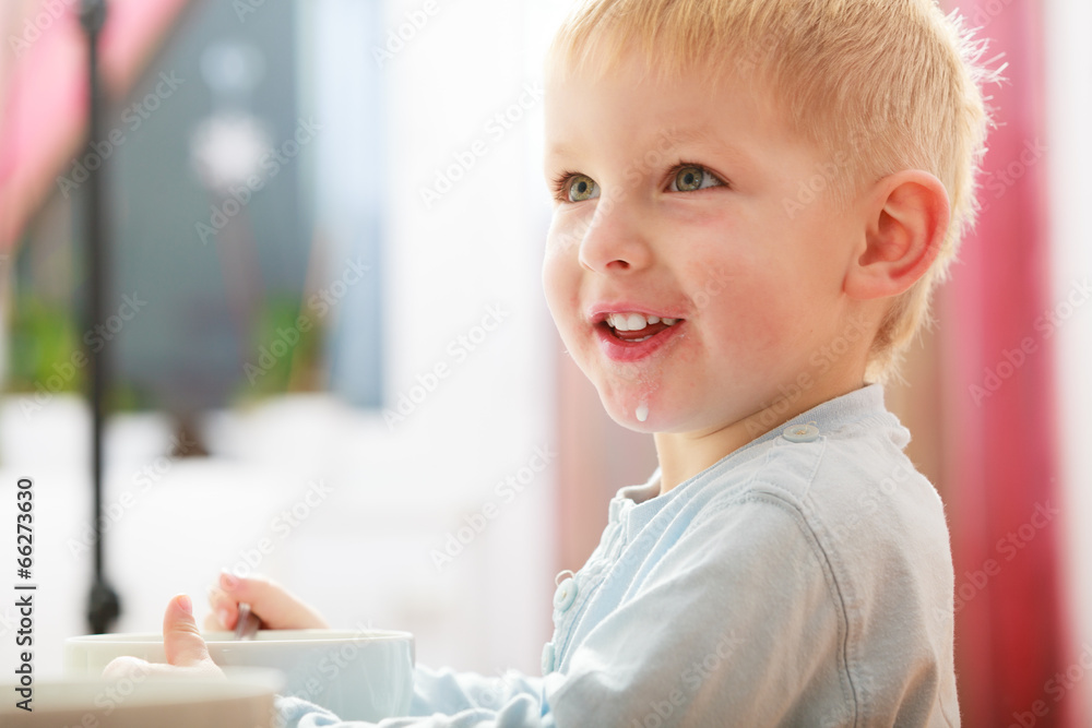 Boy kid child eating corn flakes breakfast meal at the table Boy kid child eating corn flakes breakfast meal at the table