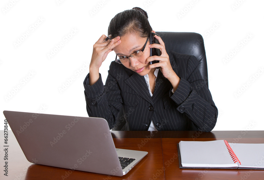 Asian businesswoman at her desk talking to a smart phone Asian businesswoman at her desk talking to a smart phone