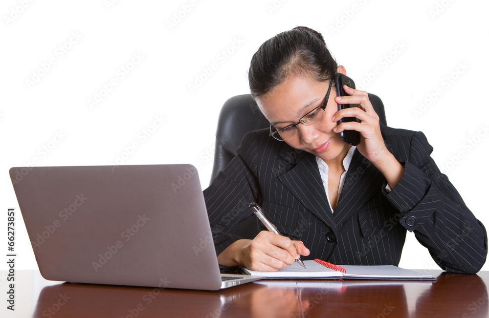 Asian businesswoman at her desk talking to a smart phone Asian businesswoman at her desk talking to a smart phone