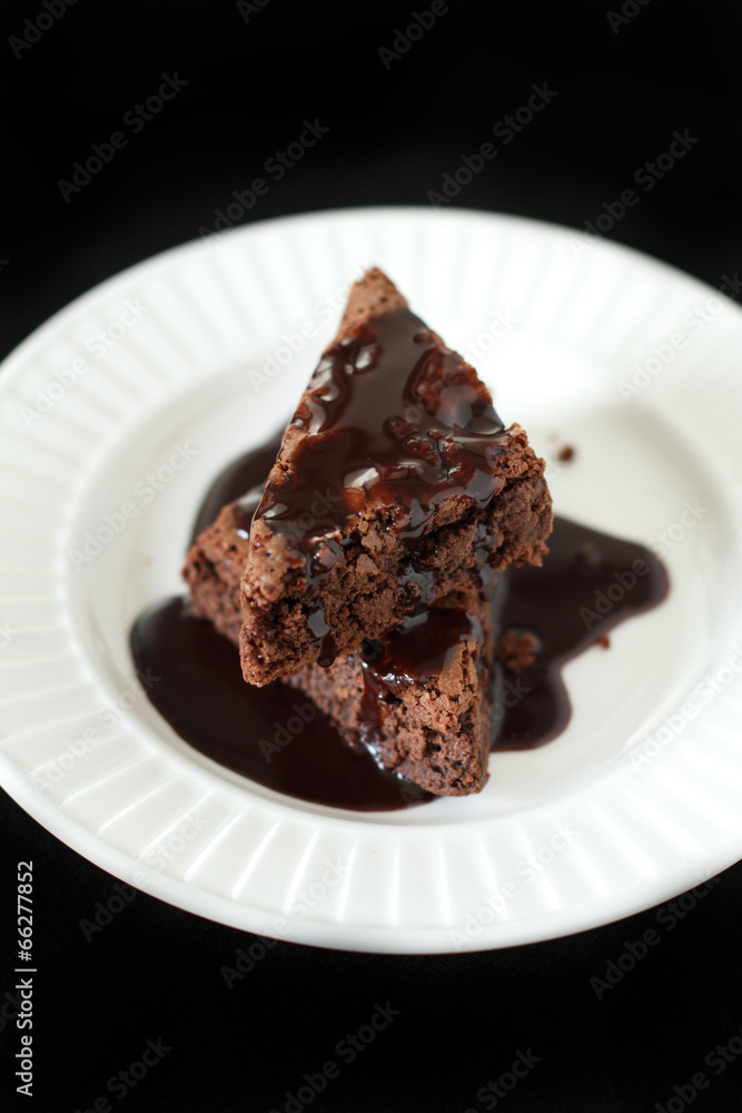 Slices of brownie on white plate covered with chocolate Slices of brownie on white plate covered with chocolate