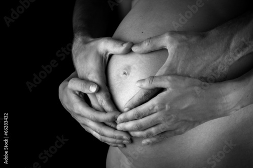 Couple making heart gestures on her pregnant belly