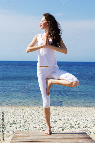 Girl doing yoga exercises on the sea coast