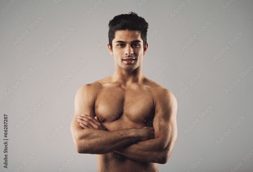 Bare-chested muscular man standing on grey background Bare-chested muscular man standing on grey background